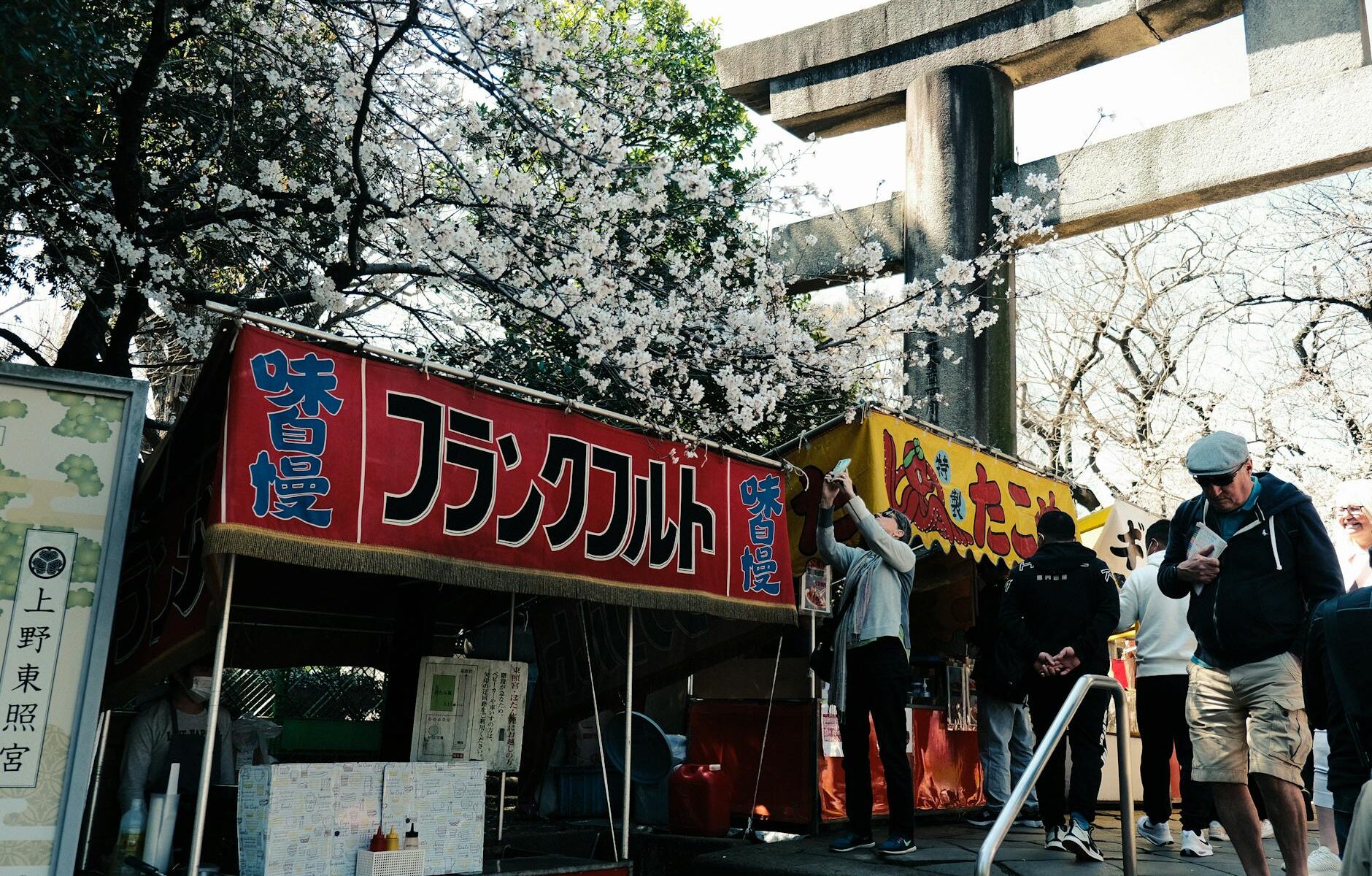 tourists walking near the gate and food stalls at the ueno toshogu shrine in tokyo japan